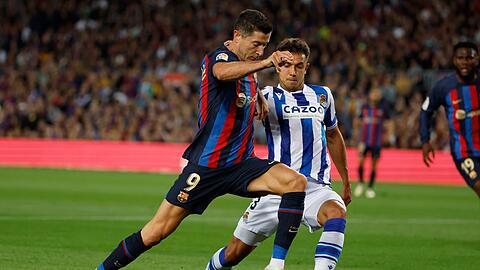 Barcelonas Robert Lewandowski (l) versucht, den Ball an Real Sociedads Martin Zubimendi vorbeizuschieben.
