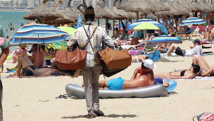 Palma de Mallorca in Spanien: Ein Händler mit gefälschten Handtaschen am Strand von El Arenal.
