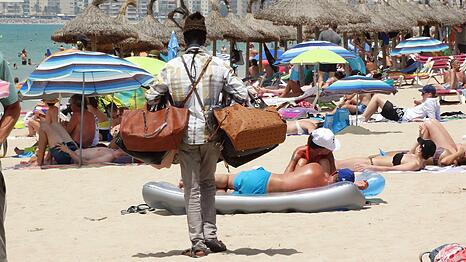 Palma de Mallorca in Spanien: Ein Händler mit gefälschten Handtaschen am Strand von El Arenal.