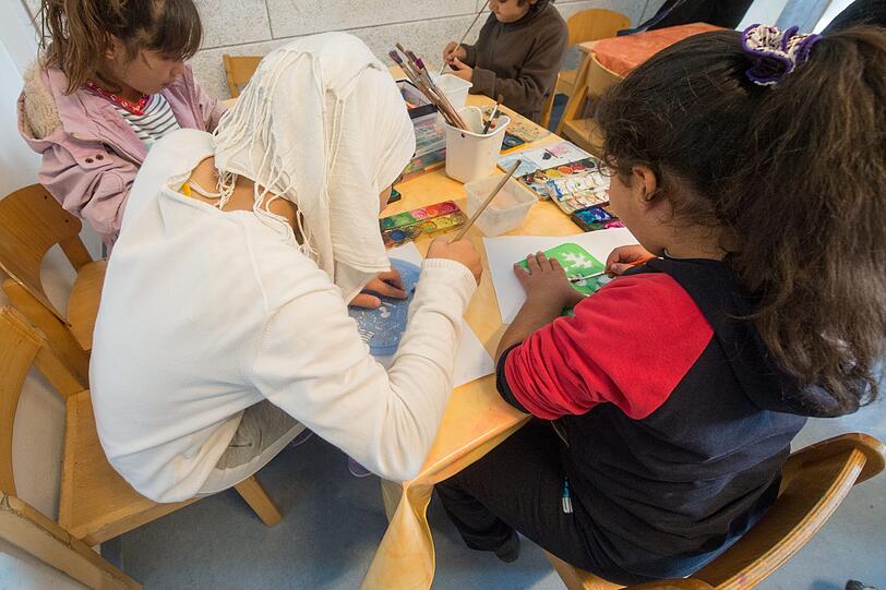 Eine Mutter malt in einer Flüchtlingsunterkunft mit ihren Kindern. (Symbolbild)