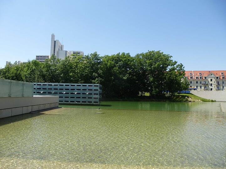 Mitten im Teich steht eine Skulptur.