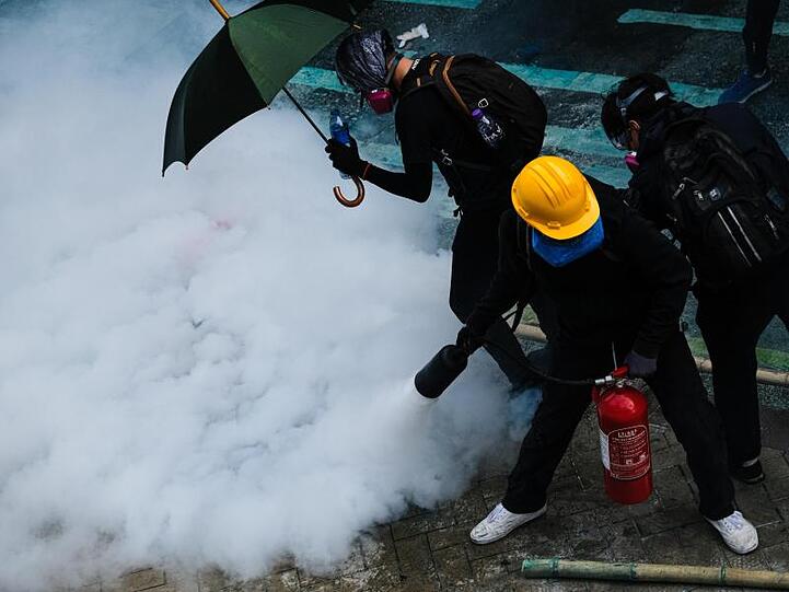 Demonstranten bekämpfen Tränengas mit einem Feuerlöscher.