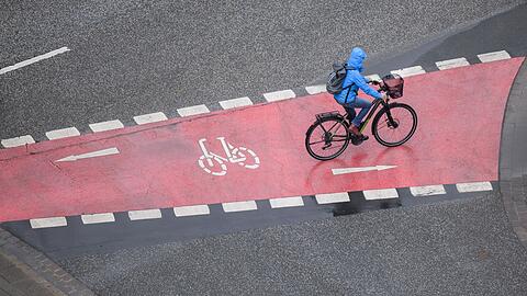 Eine Frau fährt bei Regen mit einem Fahrrad.