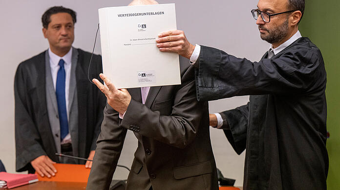 Die türkische Übersetzung fehlte, ein neuer Termin wurde gesucht: Die Anwälte Ömer Sahinci (l) und Adam Ahmed (r) stehen beim ersten Prozessauftakt im Dezember 2024 bei ihrem Mandanten im Gerichtssaal.