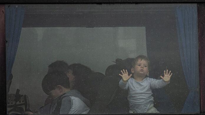 Ein Kind steht im Fenster eines Busses, der am Grenzübergang Porubne in der Westukraine auf die Überfahrt nach Rumänien wartet.