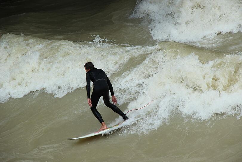 Hochwasser für die einen, perfekte Wellen für die anderen. Waghalsig tummeln sich Sportler in der Isar.