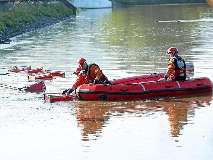 Hilfskräfte arbeiten im Wasser unterhalb des Staudams.
