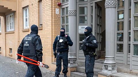 Ein Polizist geht bei einer Razzia mit einem Bolzenschneider in ein Haus in der Hauptstadt. Mit einer Großrazzia ist die Polizei am Donnerstag gegen Clankriminalität in Berlin und Umgebung vorgegangen.