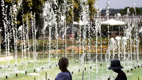 Zwei Frauen sitzen an einem Springbrunnen im egapark in Erfurt in Thüringen.