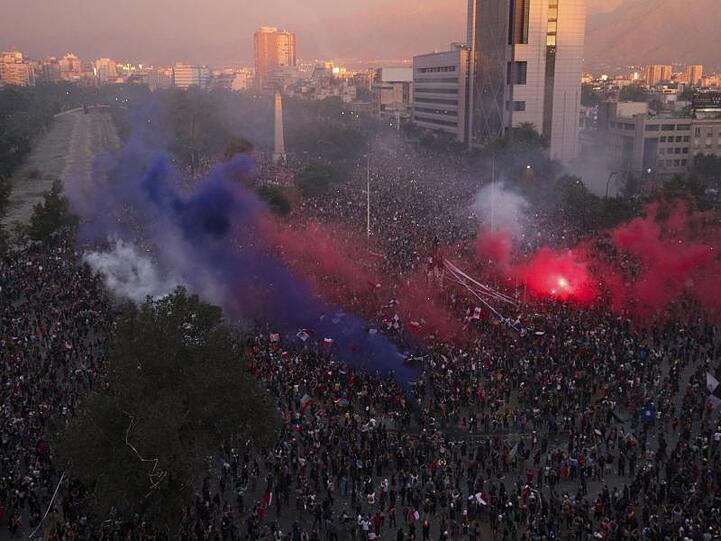 Rauchwolken von Fackeln steigen über einer riesigen Demonstration in Santiago de Chile auf.
