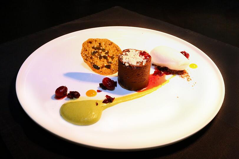 5. Gang: Schokolade, Pistazien, Cranberry, Yuzu-Eis: Ein Schokoladentörtchen, Pistaziencreme, marinierte Cranberrys und Eis aus der asiatischen Zitrusfrucht &ndash; hier bleiben keine Dessertwünsche offen. Einen Hauch Mandarine und florale Noten ergänzt die Riesling Spätlese &bdquo;Monzinger Frühlingsplätzchen&ldquo; vom Weingut Weber an der Nahe.