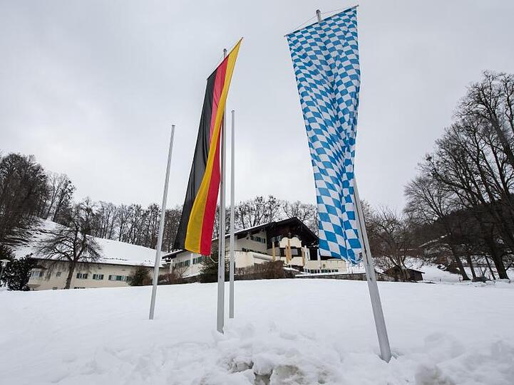Eine deutsche und eine bayerische Flagge vor dem Tagungsort Sankt Quirin. Foto: Peter Kneffel