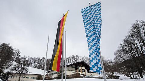 Eine deutsche und eine bayerische Flagge vor dem Tagungsort Sankt Quirin. Foto: Peter Kneffel