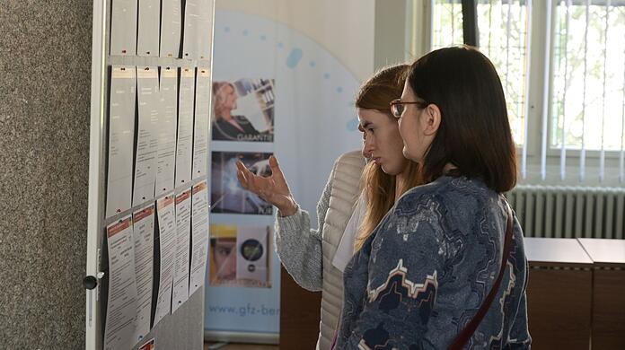 Frauen, die aus der Ukraine geflüchtet sind, informieren sich an einer Tafel über Arbeitsangebote.