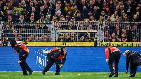 Stadionmitarbeiter sammeln Tennisbälle ein, die Fans auf das Spielfeld geworfen haben, um gegen Investoren in der DFL zu protestieren.