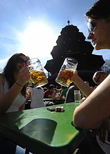 Ein junges Paar genießt das Frühlingswetter bei einem kühlen Bier im Biergarten.