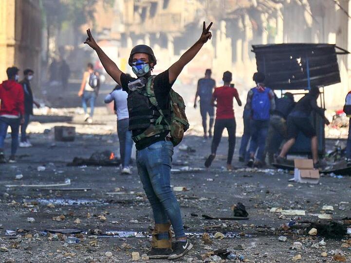 Ein regierungskritischer Demonstrant in Irak zeigt bei Zusammenstößen mit der Polizei das Victory-Zeichen. Die Proteste gegen die Regierung dauern an.