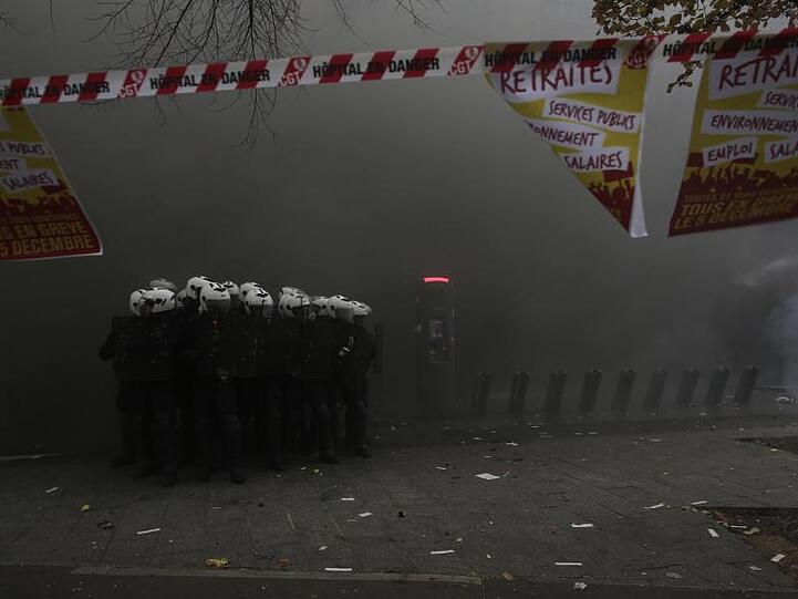 Polizisten formieren sich in Paris inmitten einer dichten Rauchwolke.