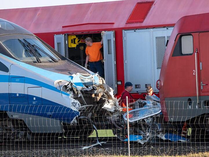 Bahnmitarbeiter stehen vor zwei zusammengestoßenen Lokomotiven. Foto: Peter Kneffel/dpa