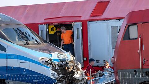 Bahnmitarbeiter stehen vor zwei zusammengestoßenen Lokomotiven. Foto: Peter Kneffel/dpa
