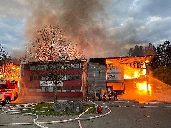 Feuerwehrleute löschen einen Firmenkomplex in Achberg, der in voller Ausdehnung brennt. Foto: Benjamin Liss/dpa
