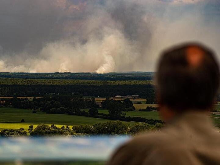 Ein Mann blickt von einem Aussichtsturm von Niedersachsen aus über die Elbe auf den Waldbrand bei Lübtheen in Mecklenburg-Vorpommern.