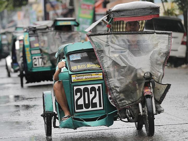 Dreirädrige Mopeds fahren mit Regenschutz durch die Stadt Subic.