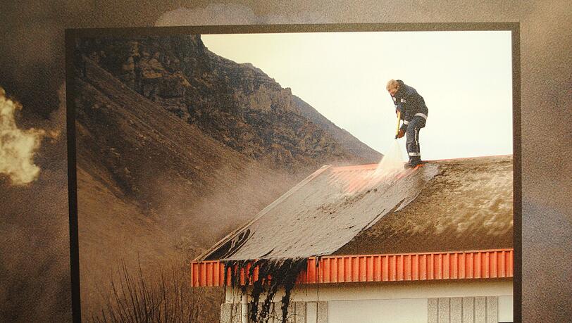 Ein Arbeiter spült die Ascheschicht des Eyjafjallajökull vom Dach des Bauernhauses. Foto aus dem Museum Ein Arbeiter spült die Ascheschicht des Eyjafjallajökull vom Dach des Bauernhauses. Foto aus dem Museum