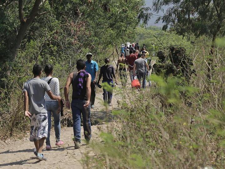 Eine Gruppe Menschen läuft über einen Feldweg von Venezuela nach Kolumbien.