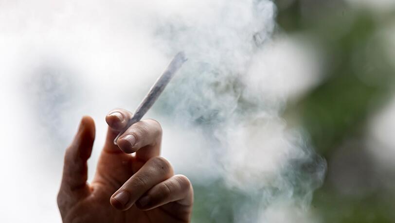 Ein Mann hält einen Joint in der Hand.