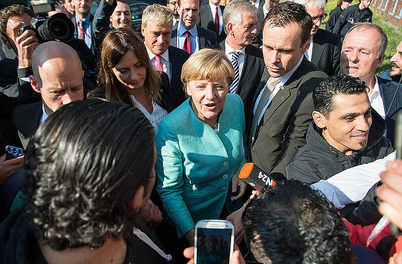 Bundeskanzlerin Angela Merkel (CDU) begrüßt am 10.09.2015 vor dem Besuch der Außenstelle des Bundesamtes für Migration und Flüchtlinge in Berlin-Spandau dort wartende Asylbewerber.