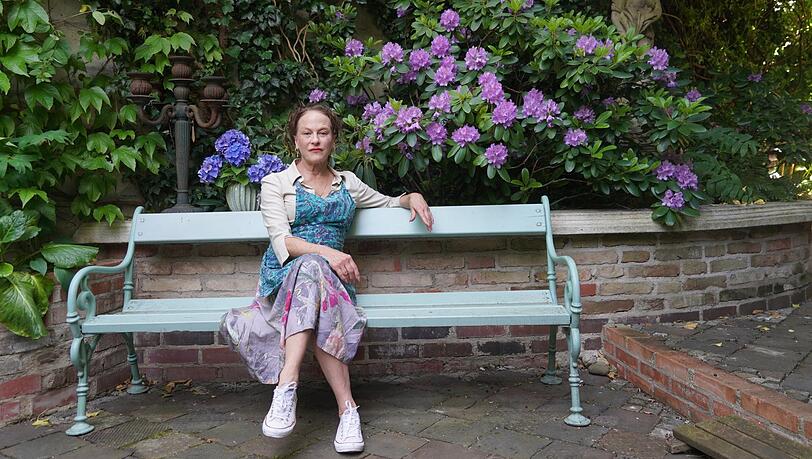 Catherine Jennings auf einer Bank in ihrem Garten. Sie liegt mit der Stadt im Clinch, wegen ihrer Gartenmauer.
