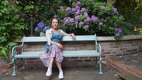 Catherine Jennings auf einer Bank in ihrem Garten. Sie liegt mit der Stadt im Clinch, wegen ihrer Gartenmauer.