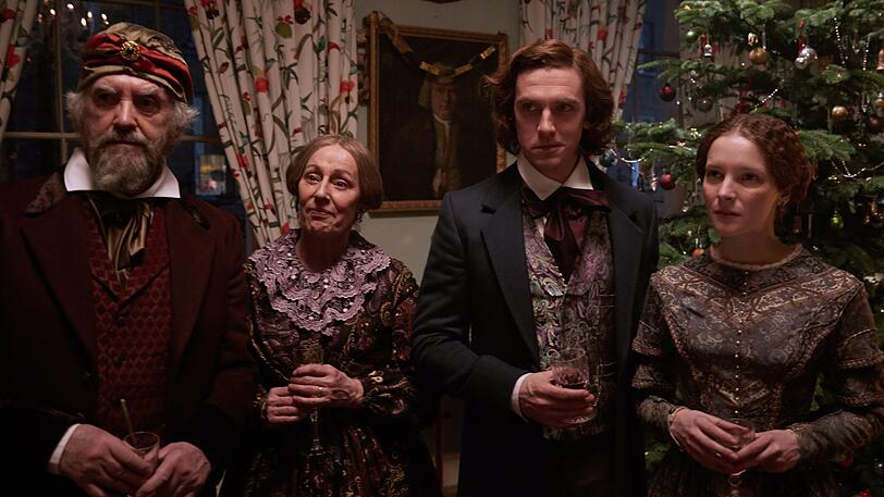 Dan Stevens als Charles Dickens (r.) mit seinem Vater (Jonathan Pryce), seiner Mutter und Frau vor einem "deutschen Weihnachtsbaum", wie seiner Familie erklärt.