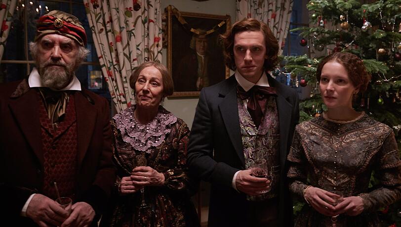Dan Stevens als Charles Dickens (r.) mit seinem Vater (Jonathan Pryce), seiner Mutter und Frau vor einem "deutschen Weihnachtsbaum", wie seiner Familie erklärt. Dan Stevens als Charles Dickens (r.) mit seinem Vater (Jonathan Pryce), seiner Mutter und Frau vor einem "deutschen Weihnachtsbaum", wie seiner Familie erklärt.