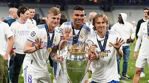 Toni Kroos (l), Carlos Casemiro (M) und Luka Modric von Real Madrid jubeln mit der Trophäe nach dem Sieg.