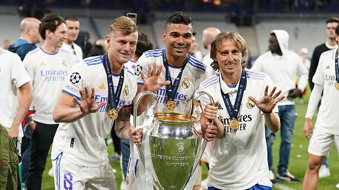 Toni Kroos (l), Carlos Casemiro (M) und Luka Modric von Real Madrid jubeln mit der Trophäe nach dem Sieg.