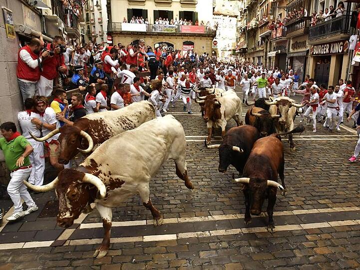 Stierläufer mit roten Halstüchern und roten Schärpen rennen während des San Fermin Festivals mit den Tieren mit.