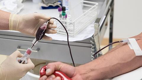 Eine Mitarbeiterin des Deutschen Roten Kreuzes einem Blutspender Blut. Foto: Christian Charisius/dpa/Symbolbild