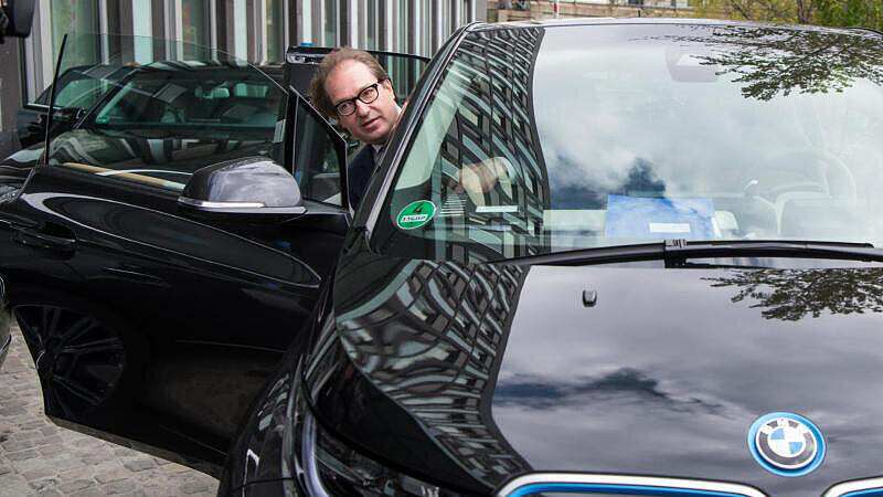 Bundesverkehrsminister Alexander Dobrindt steigt in seinen Dienstwagen, ein Elektroauto.