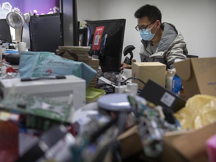 Ein Mann trägt bei der Arbeit in einem Technologieunternehmen in Peking einen Mundschutz.