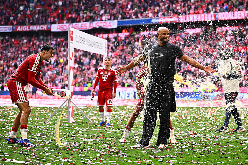 Vincent Kompany bekommt bei der Meisterfeier von Aleksandar Pavlovic (l.) und anderen Spielern eine Bierdusche.