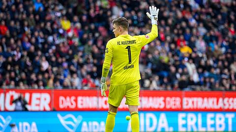 Augsburgs Torwart Finn Dahmen gestikuliert, nachdem Tennisbälle auf das Spielfeld geworfen wurden. Die Fans protestieren gegen den von der Deutschen Fußball Liga (DFL) angestrebten Investoren-Einstieg. Der DFB hat Augsburg wegen des Vorfalls mit einer Geldstrafe belegt.