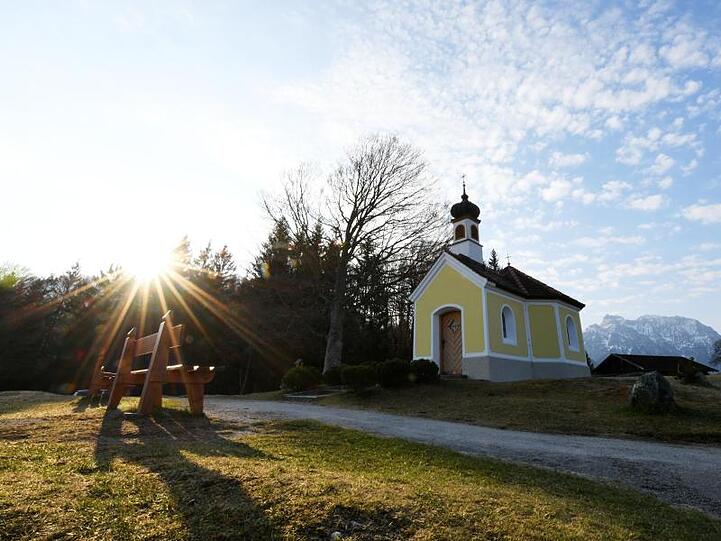 Die Sonne geht hinter einer Kapelle auf. Foto: Angelika Warmuth/dpa