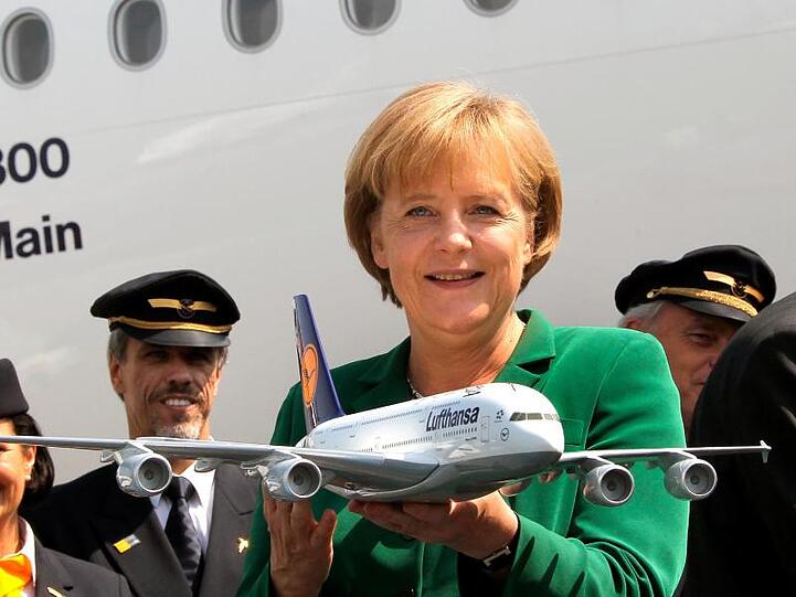 Lachend hält Bundeskanzlerin Angela Merkel (CDU) 2010 auf der Internationalen Luft- und Raumfahrtausstellung (ILA) auf dem Flughafen Berlin-Schönefeld ein Modell des Airbus A380 in den Händen.