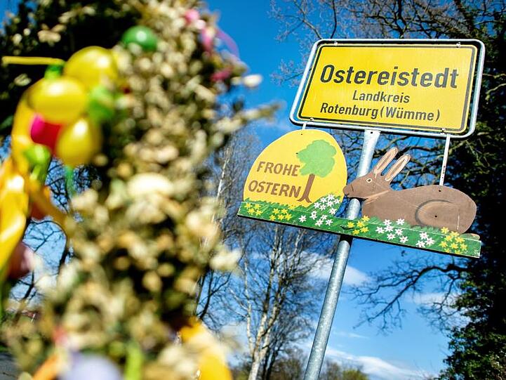 Ein Schild mit der Aufschrift "Frohe Ostern" hängt unter dem Ortsschild am Ortseingang von Ostereistedt.