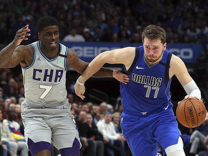 Dwayne Bacon (7/l) von den Charlotte Hornets attackiert Mavs-Spieler Luka Doncic (77).