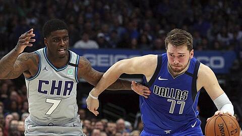 Dwayne Bacon (7/l) von den Charlotte Hornets attackiert Mavs-Spieler Luka Doncic (77).