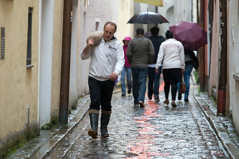 Ein Mann trägt am 01.06.2013 in der Altstadt von Passau einen gefüllten Sandsack. Extreme Regenfälle verschärfen die Hochwasserlage in Bayern und führen zu Überschwemmungen. Foto: Armin Weigel