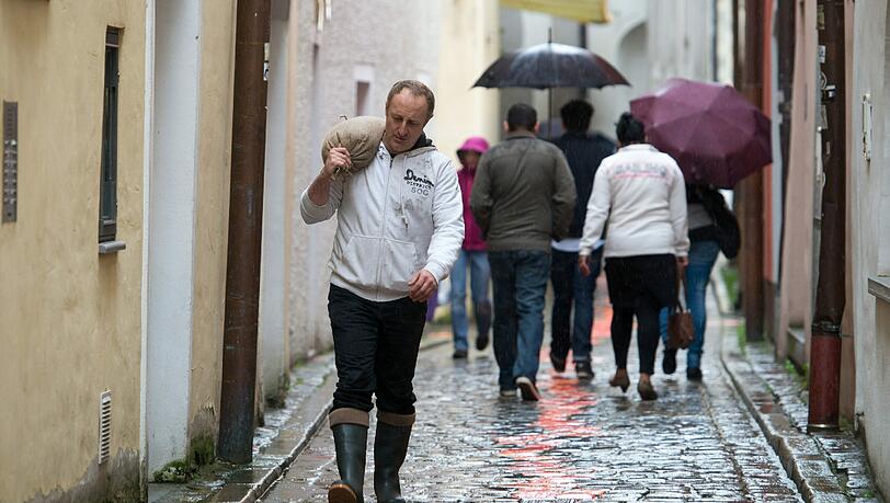 Ein Mann trägt am 01.06.2013 in der Altstadt von Passau einen gefüllten Sandsack. Extreme Regenfälle verschärfen die Hochwasserlage in Bayern und führen zu Überschwemmungen. Foto: Armin Weigel Ein Mann trägt am 01.06.2013 in der Altstadt von Passau einen gefüllten Sandsack. Extreme Regenfälle verschärfen die Hochwasserlage in Bayern und führen zu Überschwemmungen. Foto: Armin Weigel